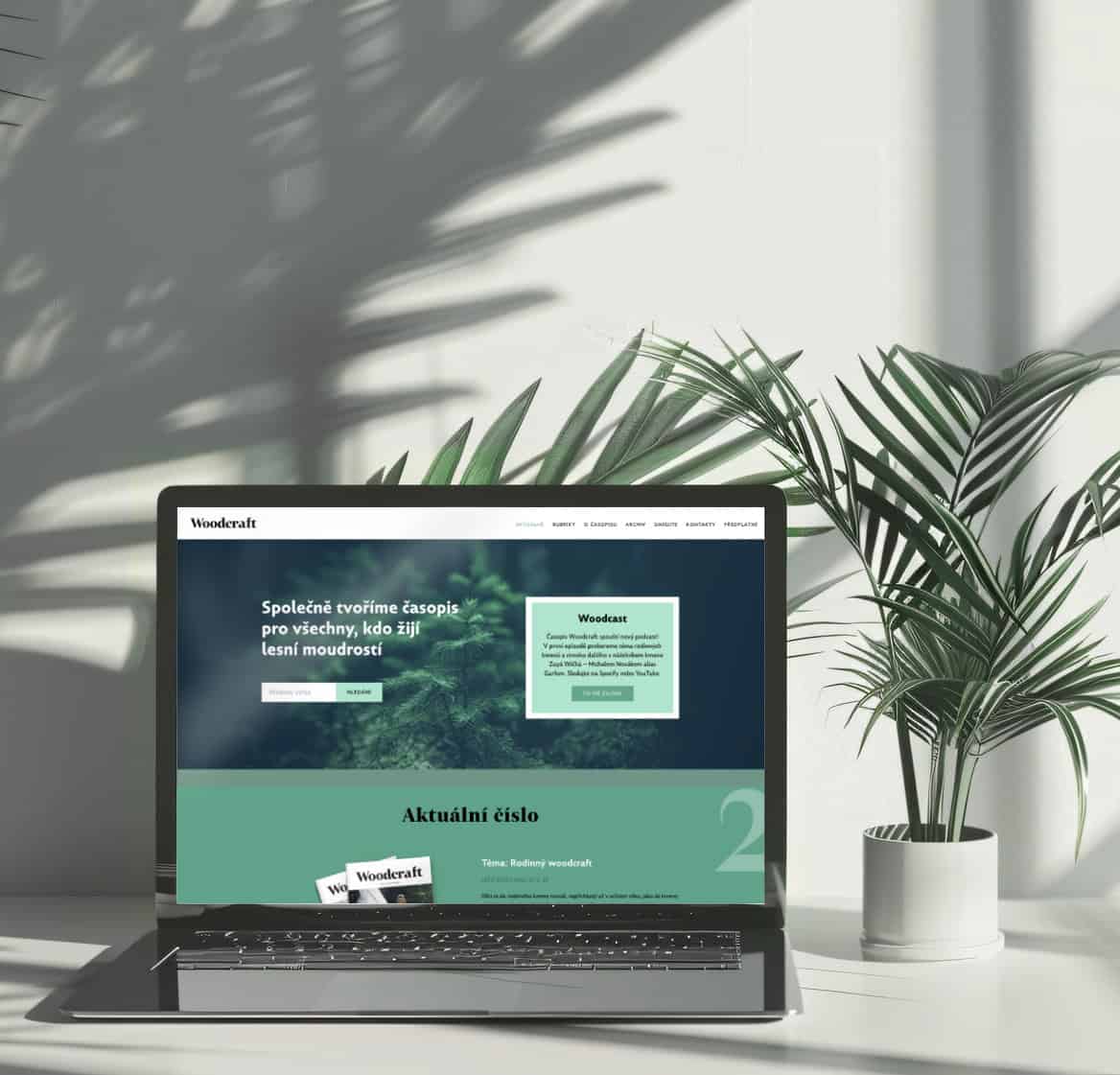 Green forest-themed website displayed on a laptop screen with a potted plant nearby.