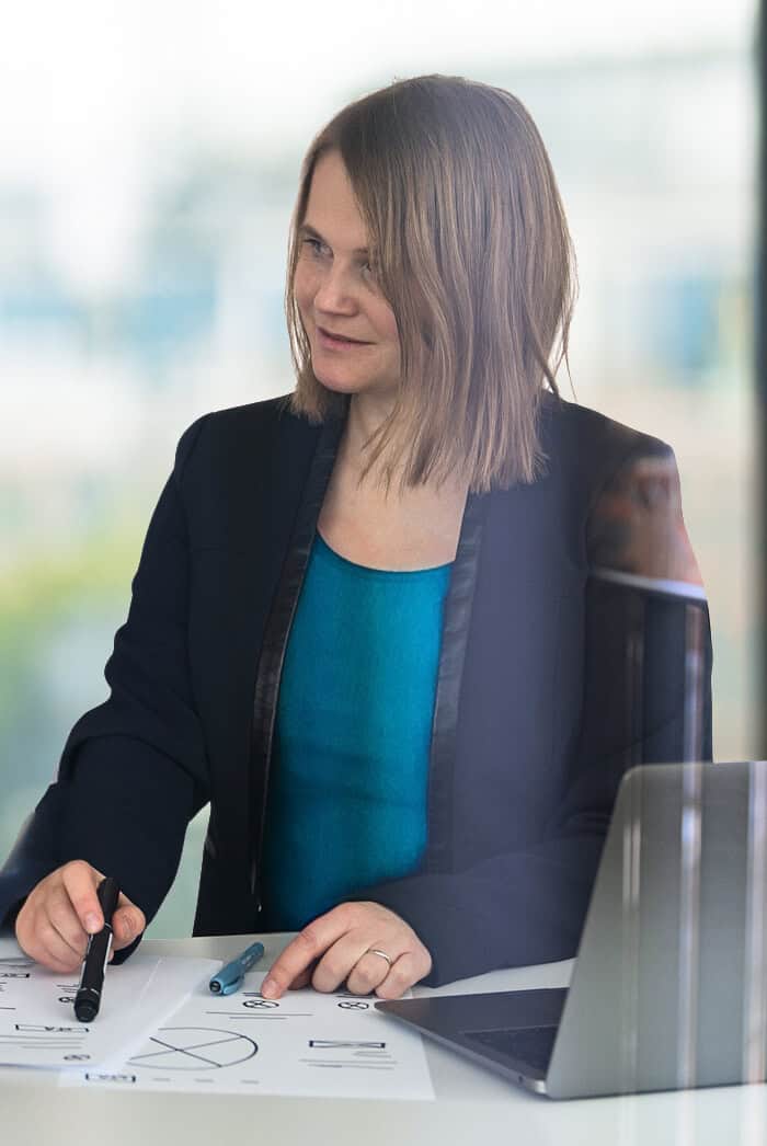 Barbora consulting, sitting at a desk and showing a client wireframes.