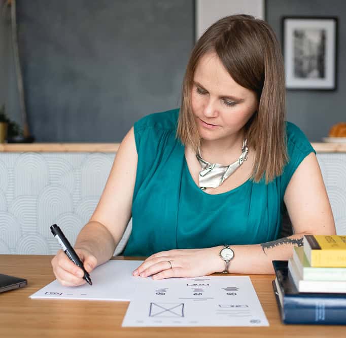 Barbora sitting at a desk and drawing the wireframes of a website, deep at work, preparing website design.